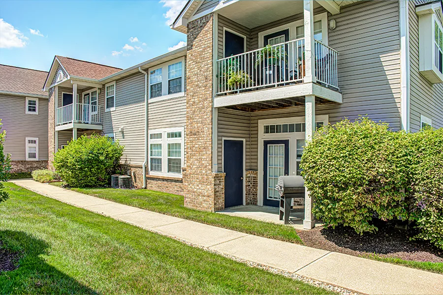An exterior view of apartment patios and balconies with plants and a grill on them at Bayshore Apartments