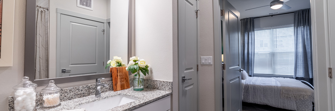 Stylish apartment bathroom with view into master bedroom